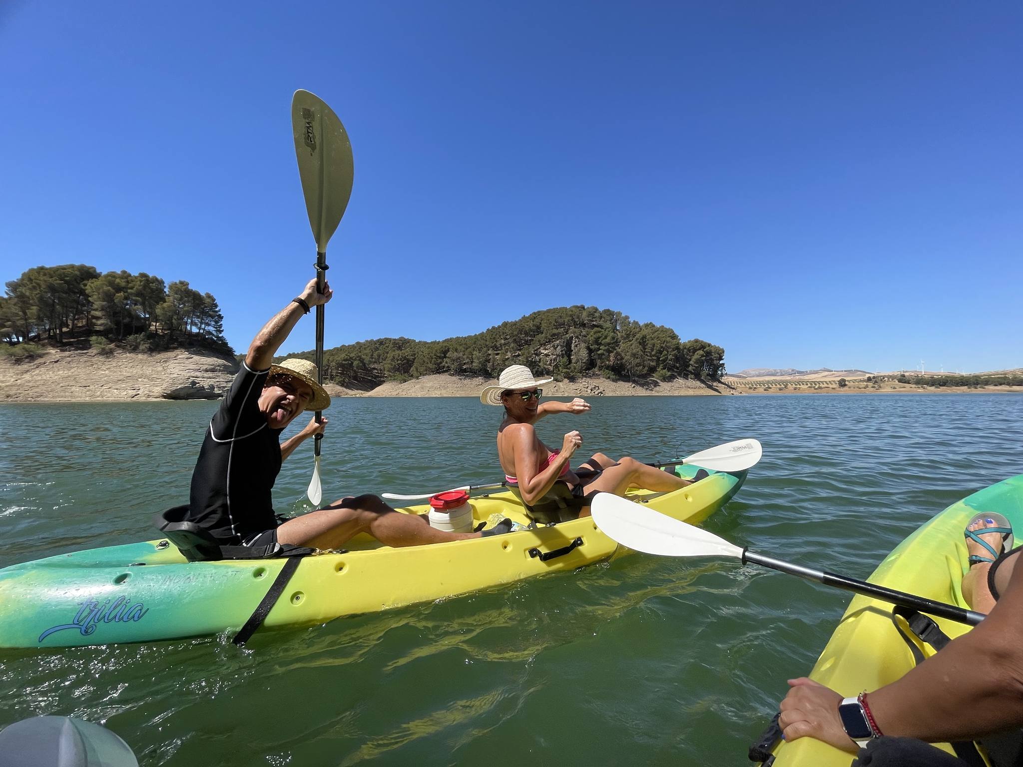 Socios del club remando en kayak, pala en alto, por el embalse